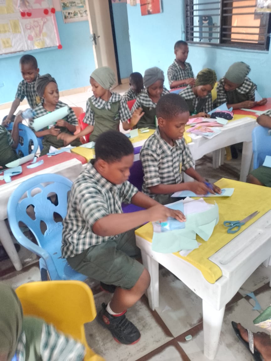 ACES pupils cutting and folding coloured paper during a craft workshop
